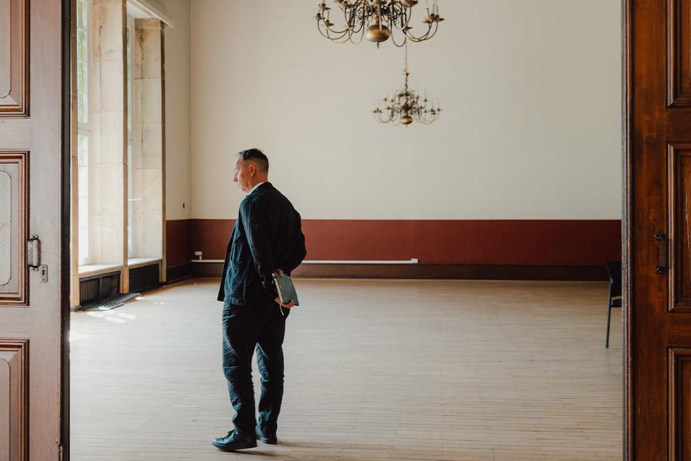 Ein Mann der im großes Saal mit Pakettboden steht 