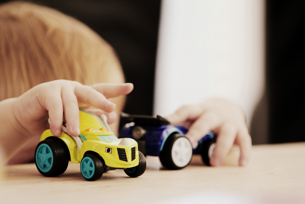 Kind spielt mit Spielzeugautos auf dem Tisch