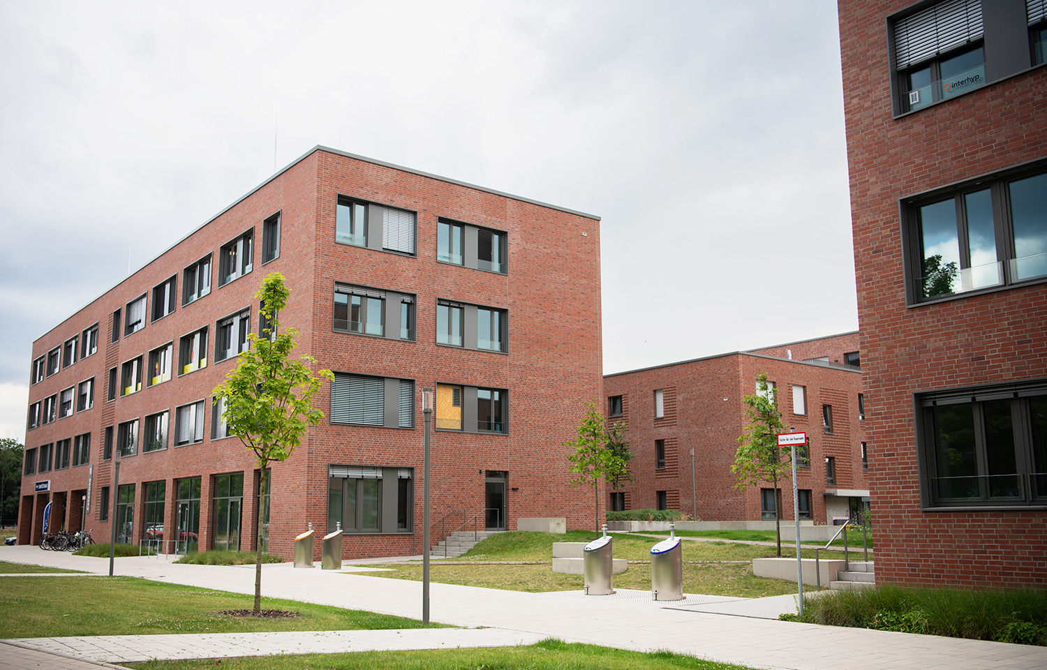 Blick auf die Backsteinbauten von CM Immobilien. Dazwischen verläuft eine grüne Achse.