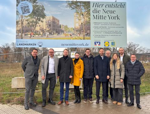 Gruppe Menschen vor einem Bauschild